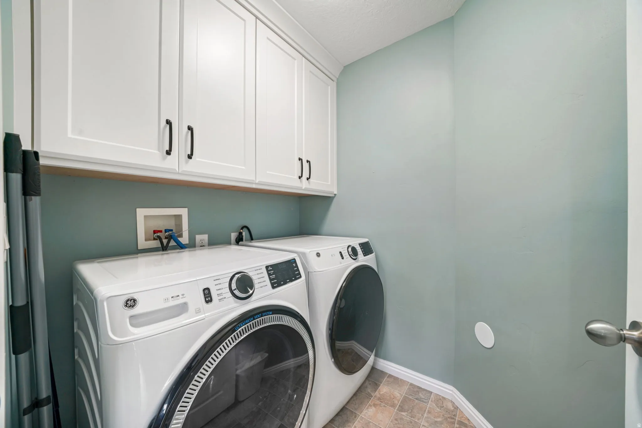 Laundry area featuring cabinet space, washer and dryer, and stone finish floors