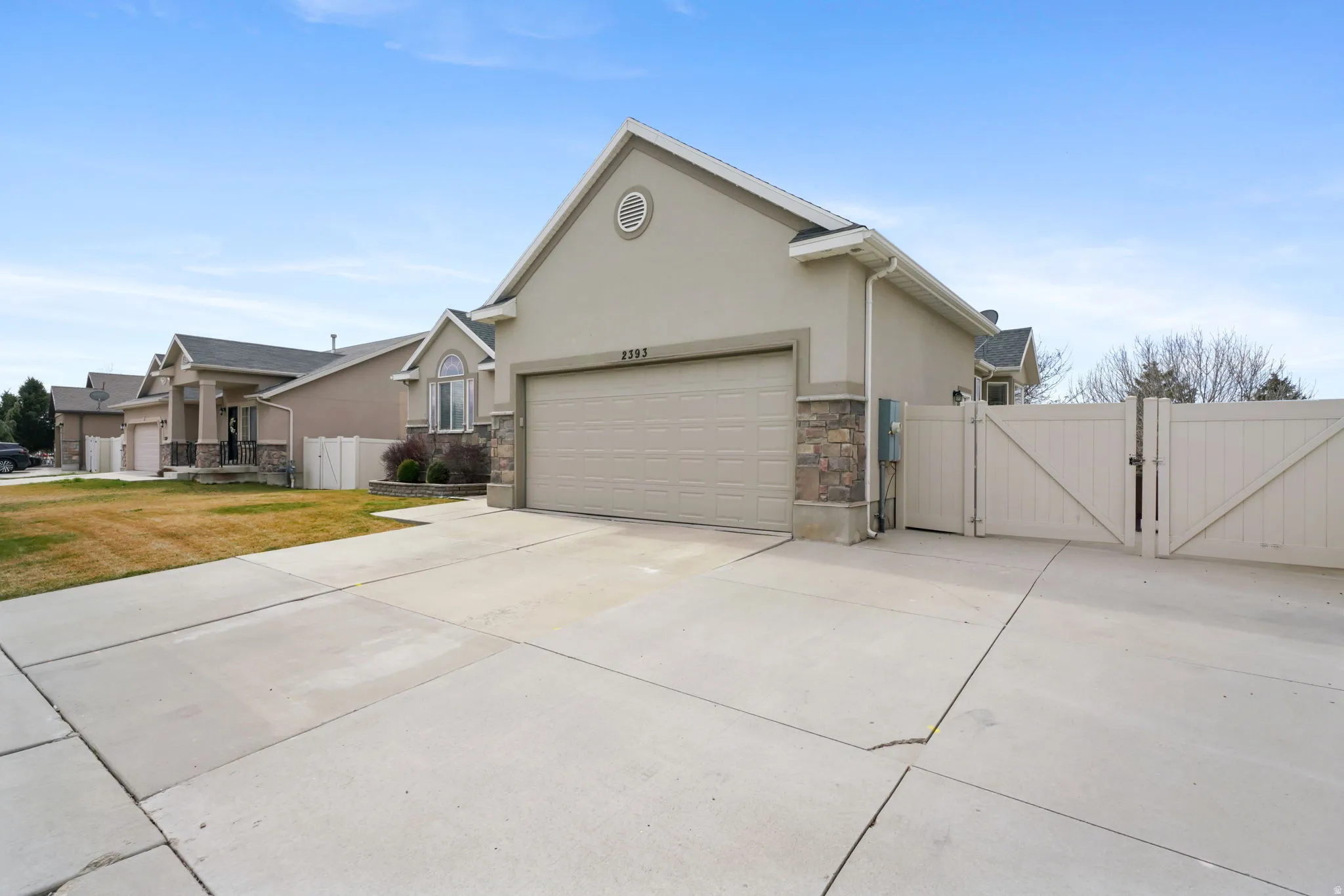 View of front of home with a gate, stucco siding, concrete driveway, stone siding, and a garage