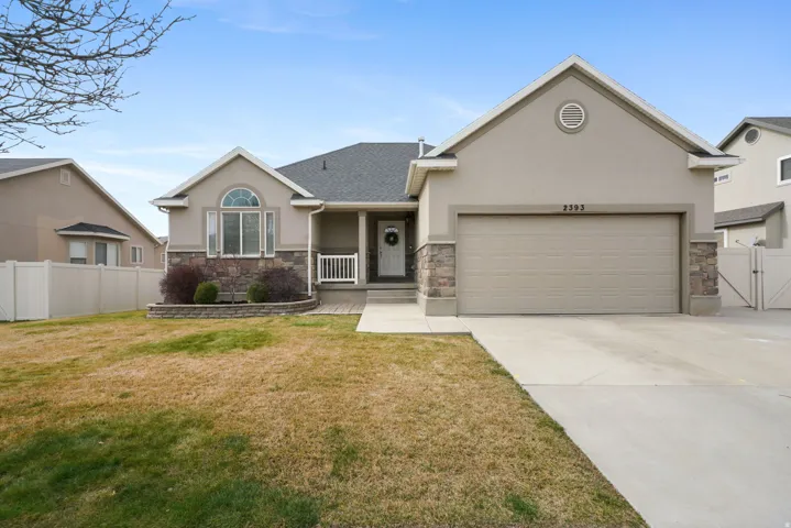 View of front of property featuring a gate, stucco siding, stone siding, and an attached garage