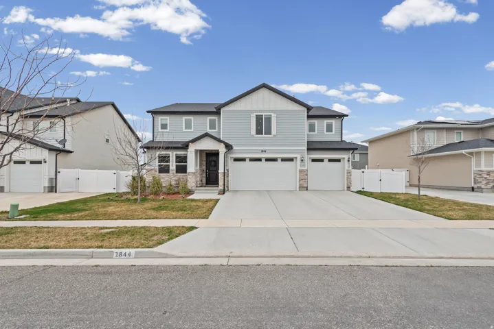 Craftsman inspired home featuring a gate, an attached garage, board and batten siding, driveway, and stone siding