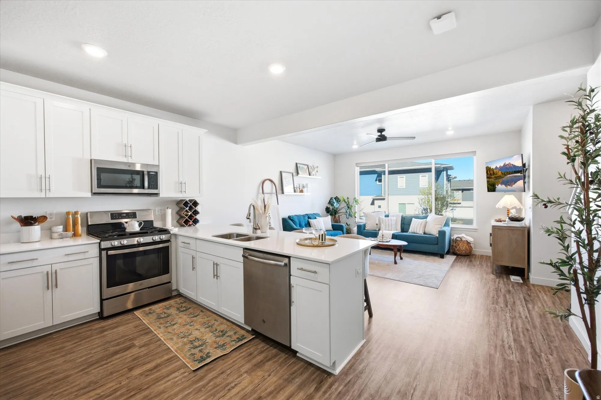 Kitchen with stainless steel appliances, open floor plan, white cabinets, a peninsula, and recessed lighting