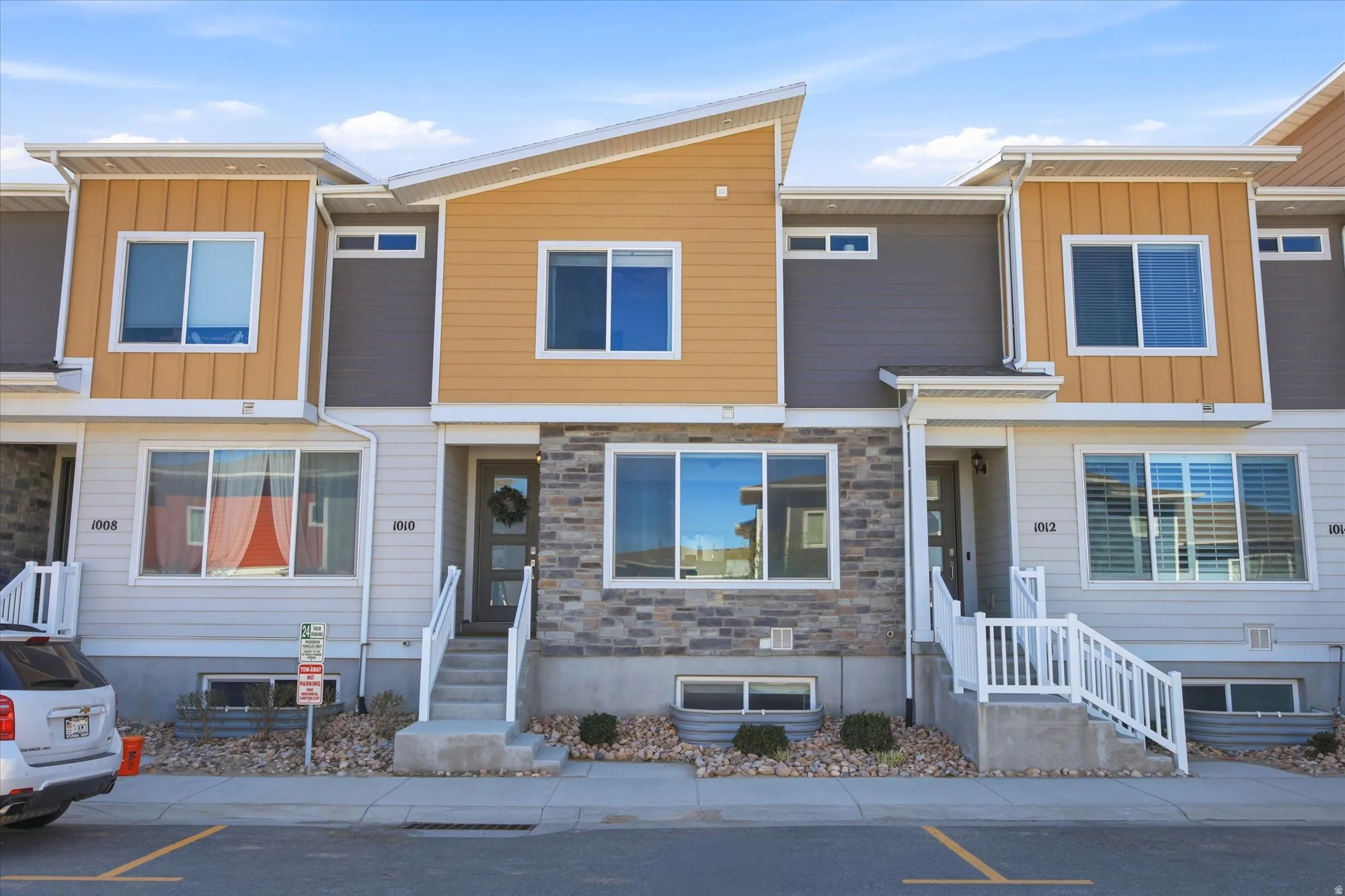 Contemporary house featuring board and batten siding, stone siding, and uncovered parking