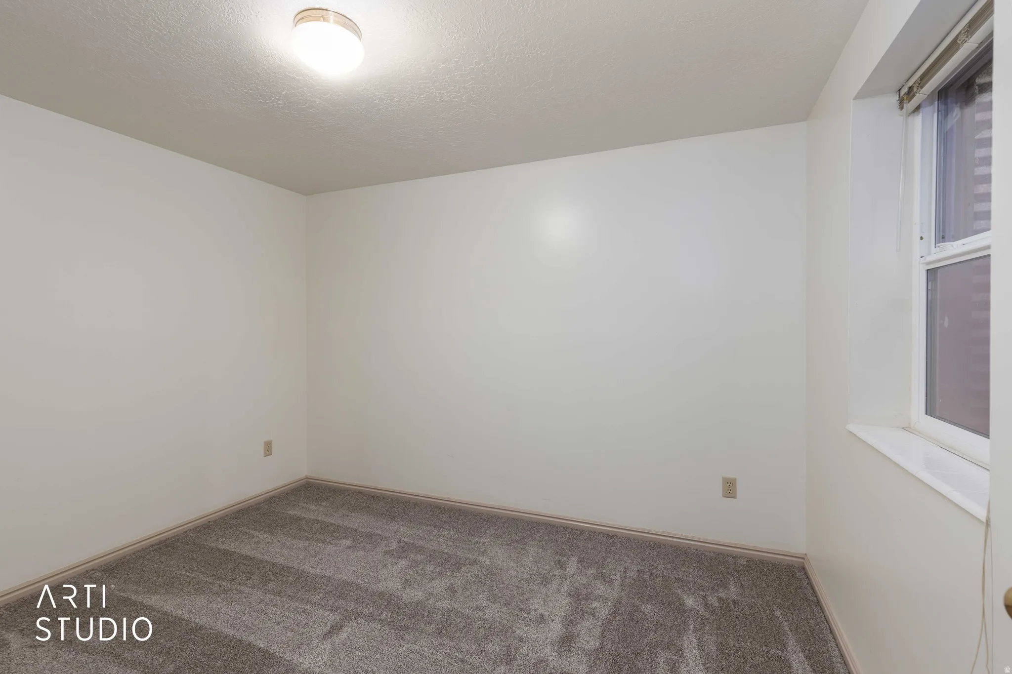 Carpeted spare room featuring a textured ceiling and baseboards