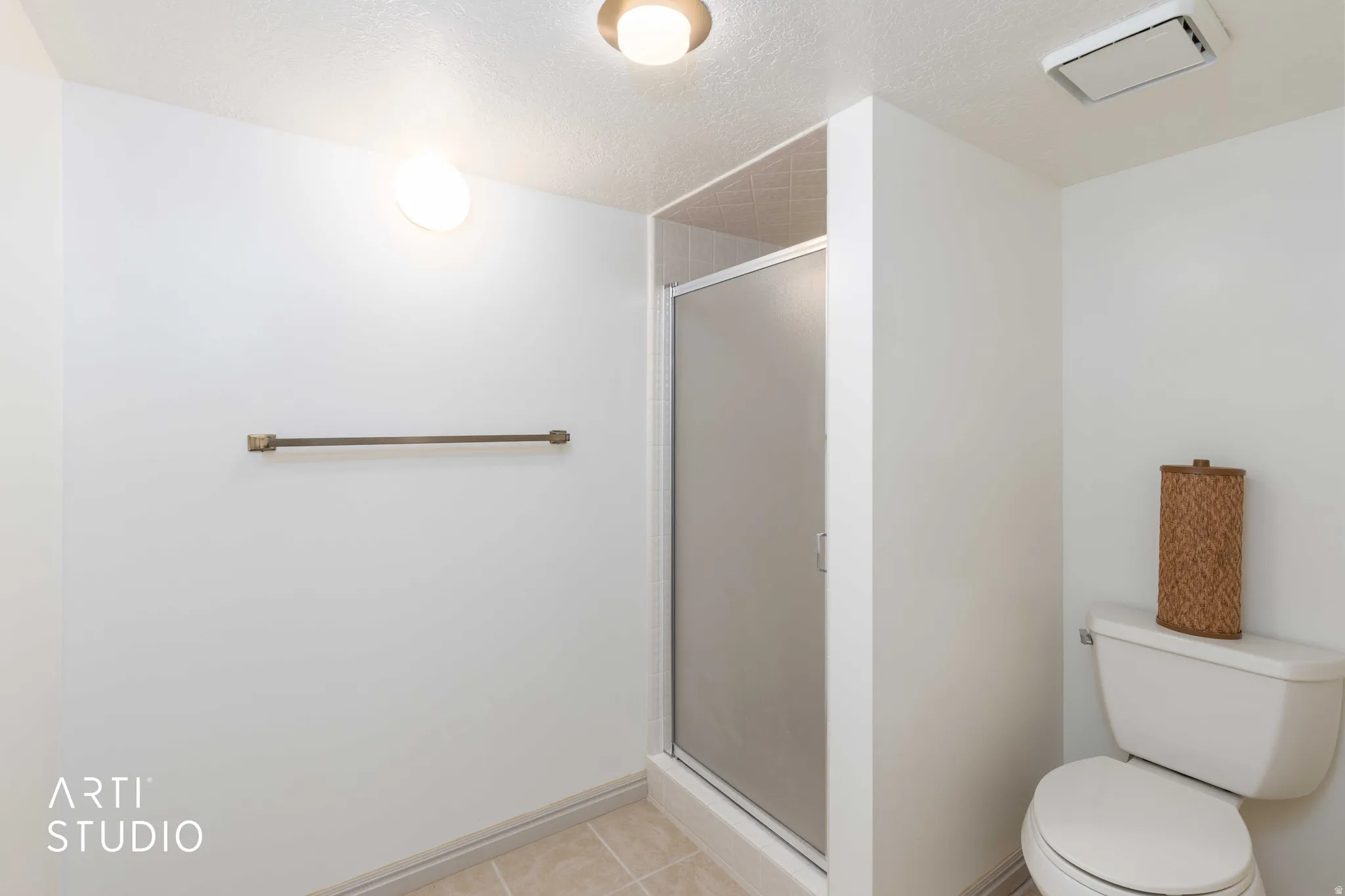Bathroom with a textured ceiling, a stall shower, and light tile patterned floors