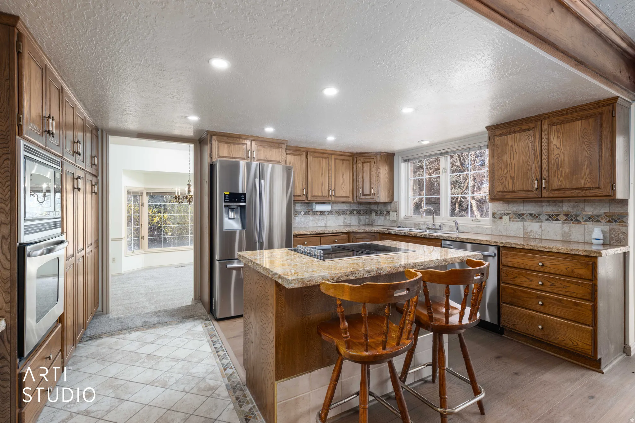 Kitchen featuring recessed lighting, wood finish cabinetry, backsplash, stainless steel appliances, and a center island