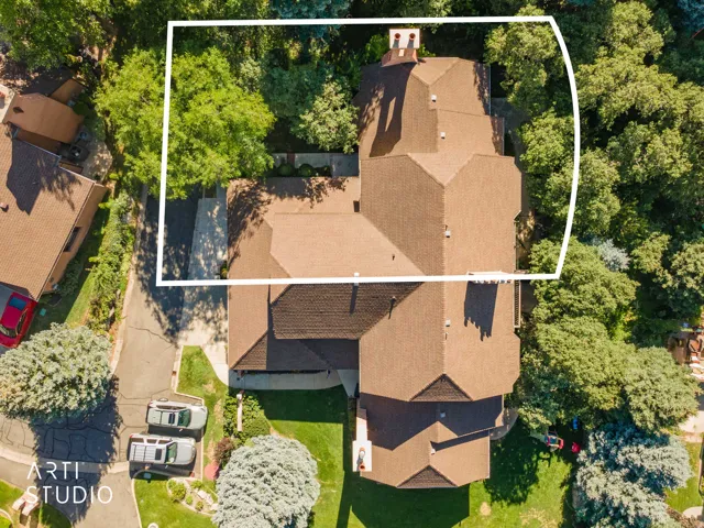 Expansive property with a multi-gabled roofline, multiple chimneys, and mature trees