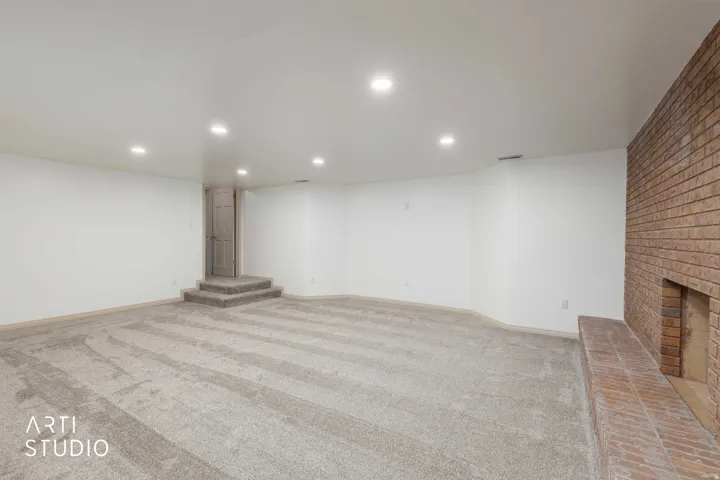 Finished basement with recessed lighting, light colored carpet, and a brick fireplace