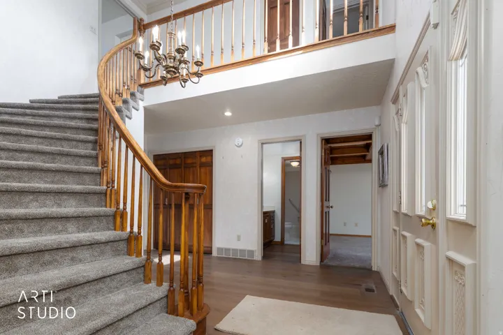 Stairway featuring wood finished floors and suspended lighting