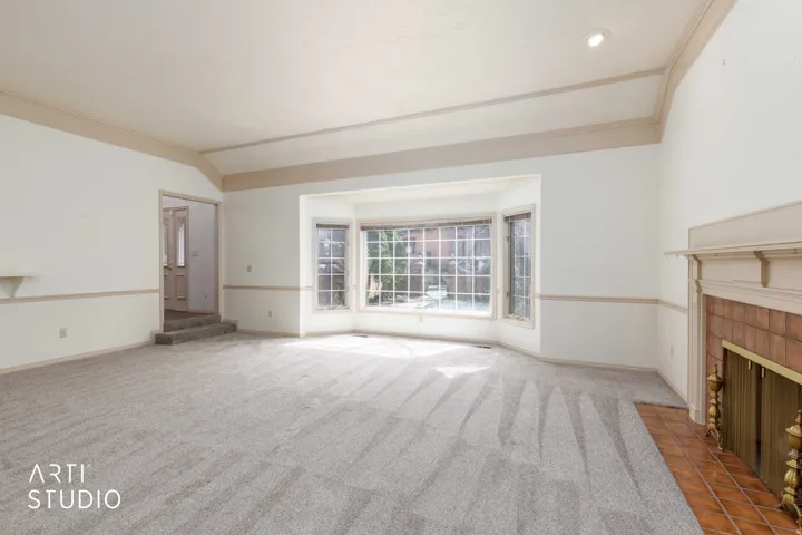 Unfurnished living room featuring carpet, a fireplace, vaulted ceiling, and ornamental molding