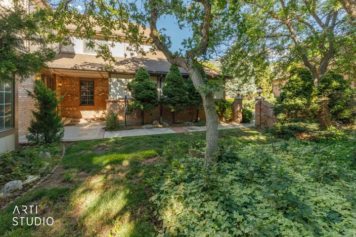 Brick exterior with a covered entry, mature trees, and established landscaping