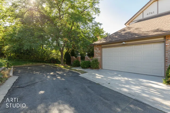 Attached garage with a panel-style door, brick exterior, and a shingle roof
