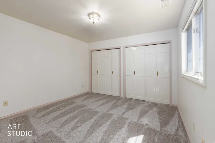 Unfurnished bedroom featuring multiple closets and light carpet