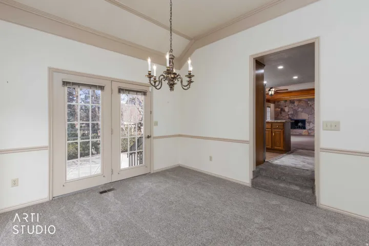 Unfurnished dining area featuring carpet, hanging lights, ornamental molding, and a fireplace