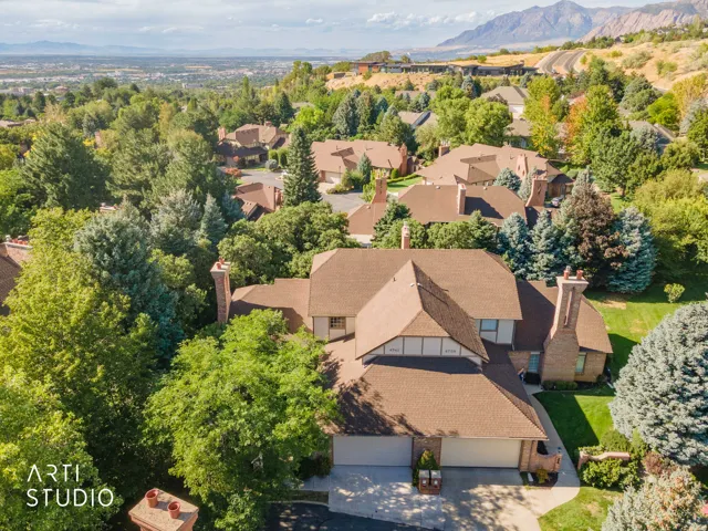 Property featuring a brown shingle roof, multiple brick chimneys, a two-car garage, and mature landscaping