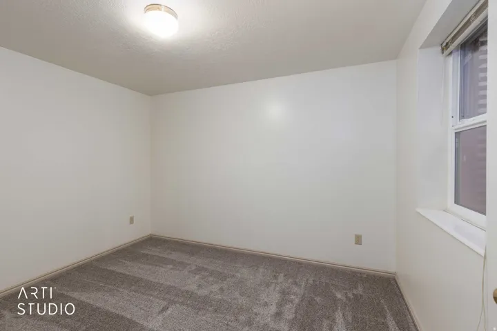 Carpeted spare room featuring a textured ceiling and baseboards