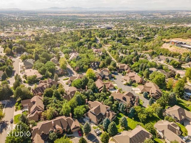 Expansive residential area featuring numerous properties with diverse architectural styles, mature trees, and mountainous terrain in the background