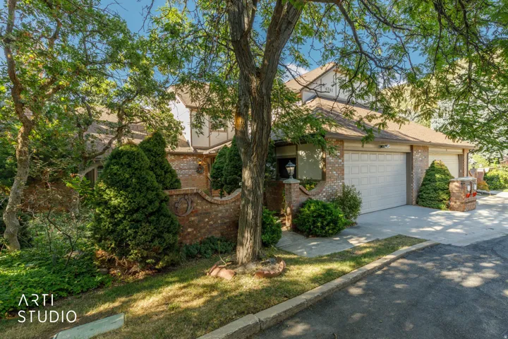 Brick exterior with white trim, two-car garage, and mature landscaping