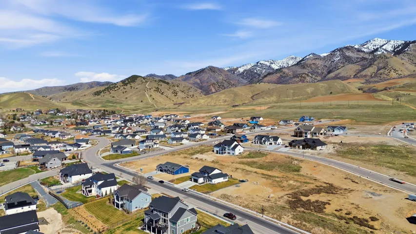 Aerial view of property and surrounding area featuring a mountain backdrop and nearby suburban area