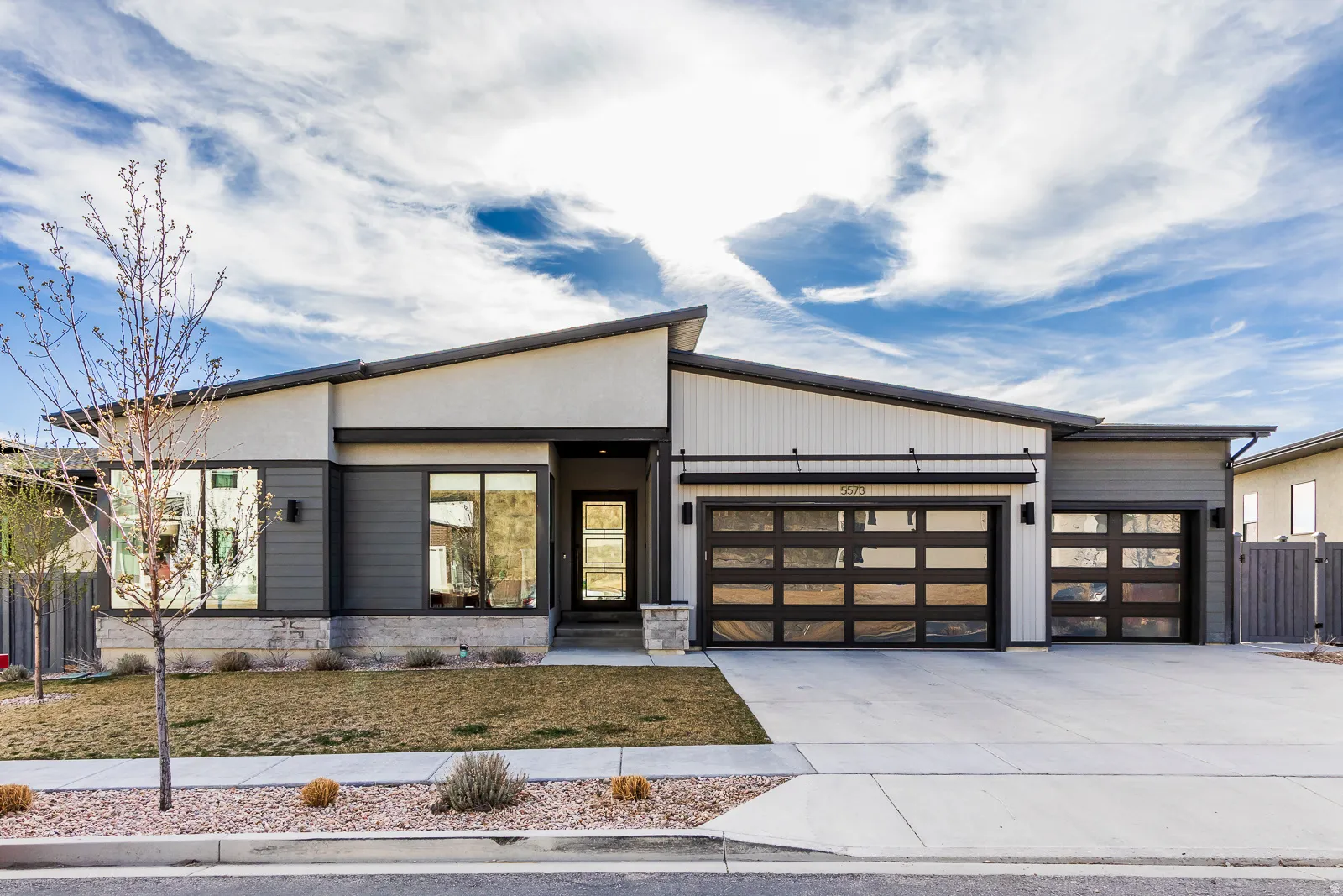 Contemporary home featuring an attached garage, driveway, and stone siding