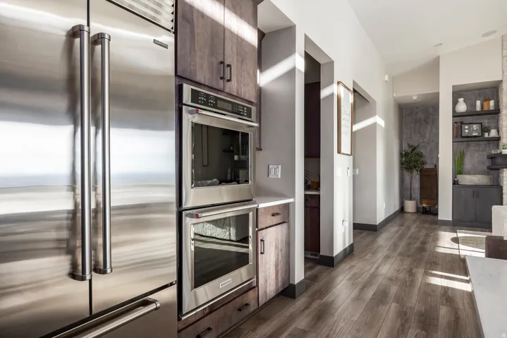 Kitchen with stainless steel appliances, dark wood-style flooring, light countertops, dark wood finish cabinetry, and vaulted ceiling