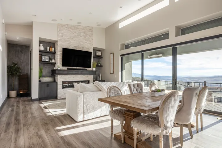 Dining space featuring light wood finished floors, a stone fireplace, and a high ceiling