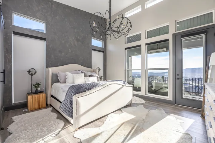 Bedroom with wood finished floors, access to outside, a high ceiling, and hanging lights