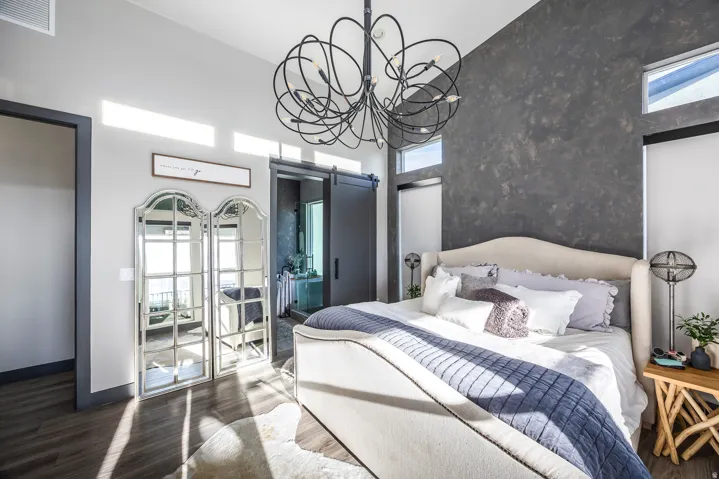 Bedroom with a barn door, dark wood-style flooring, a chandelier, connected bathroom, and a high ceiling