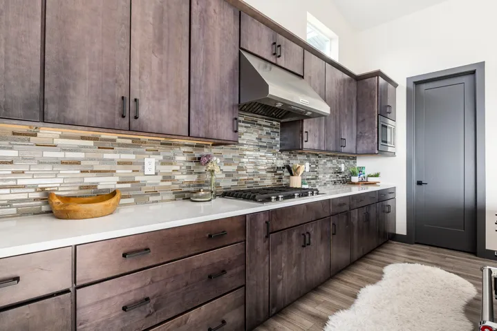 Kitchen with dark wood finish cabinetry, light wood-type flooring, stainless steel appliances, and backsplash