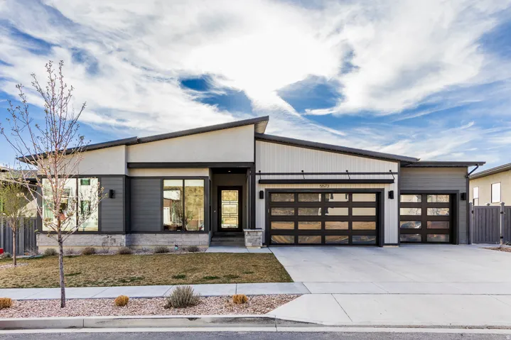 Contemporary home featuring an attached garage, driveway, and stone siding
