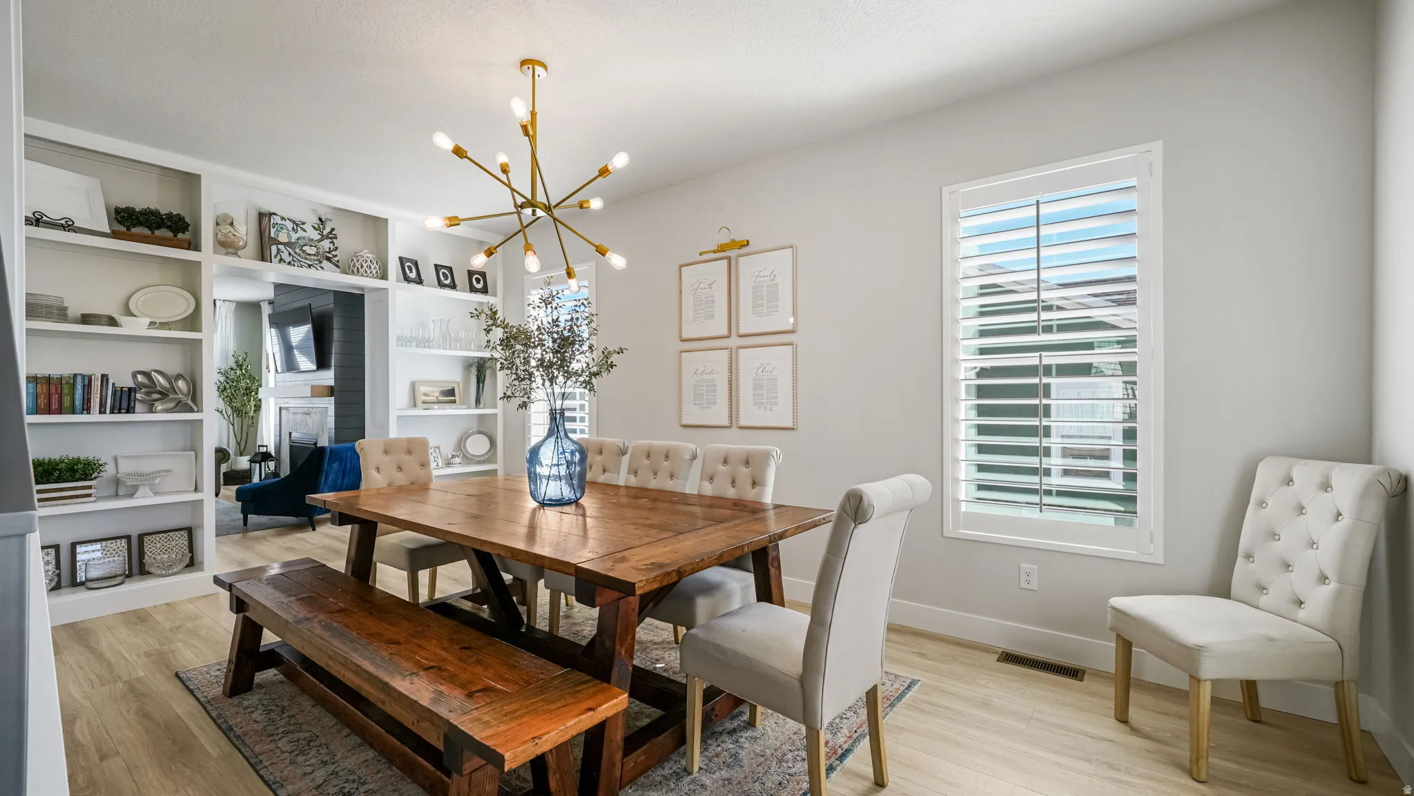 Dining space featuring light wood-style floors, hanging lights, a fireplace, and built in shelves