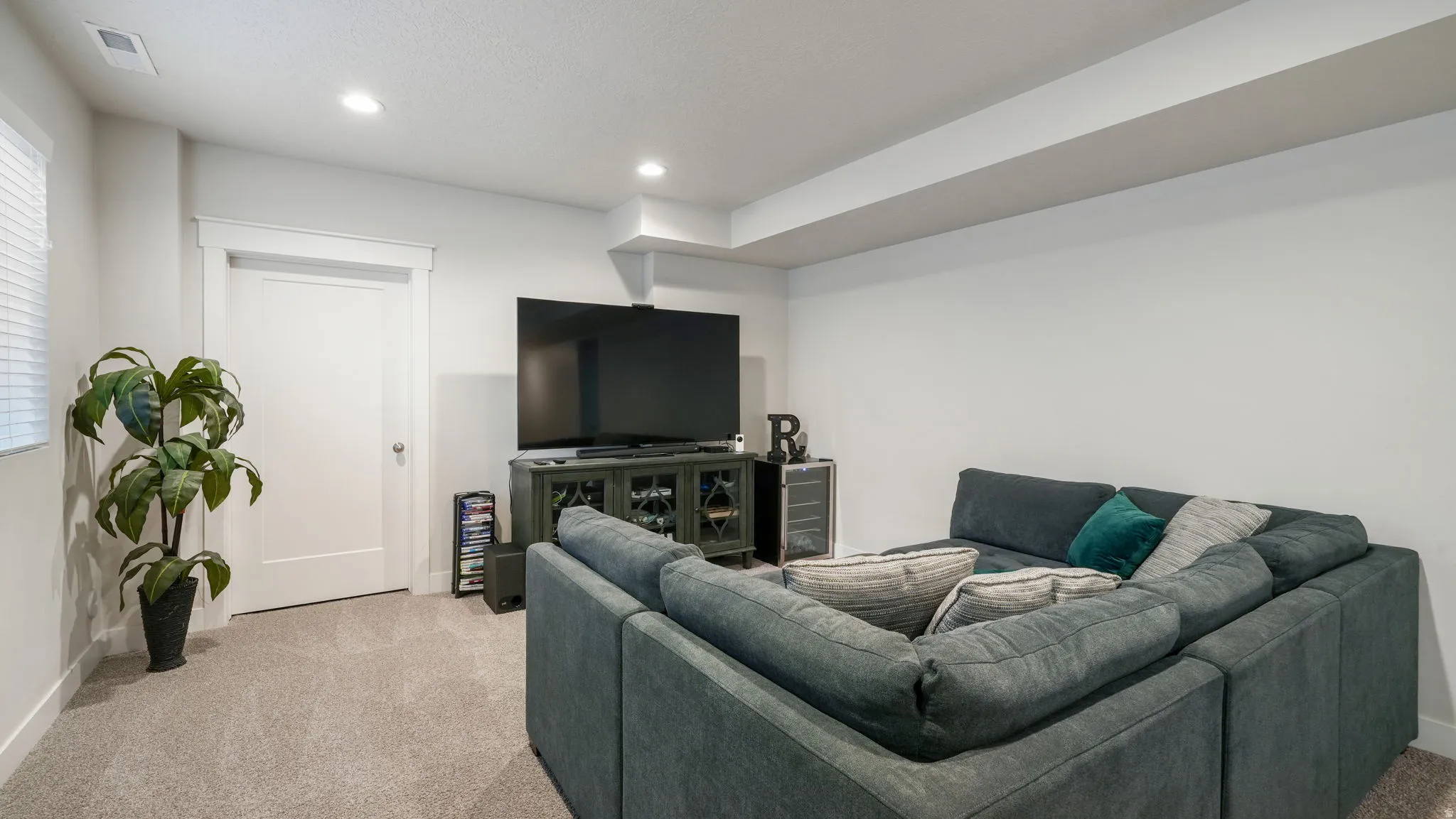 Living area with light colored carpet and recessed lighting