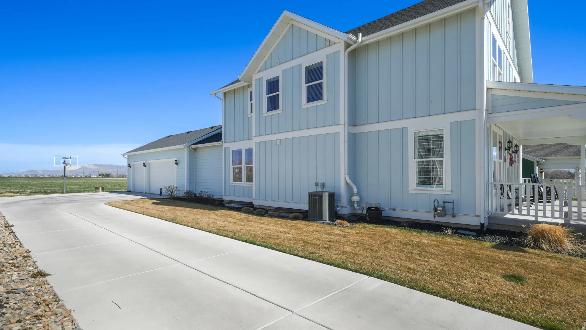 View of home's exterior with board and batten siding, a lawn, a mountain view, and driveway