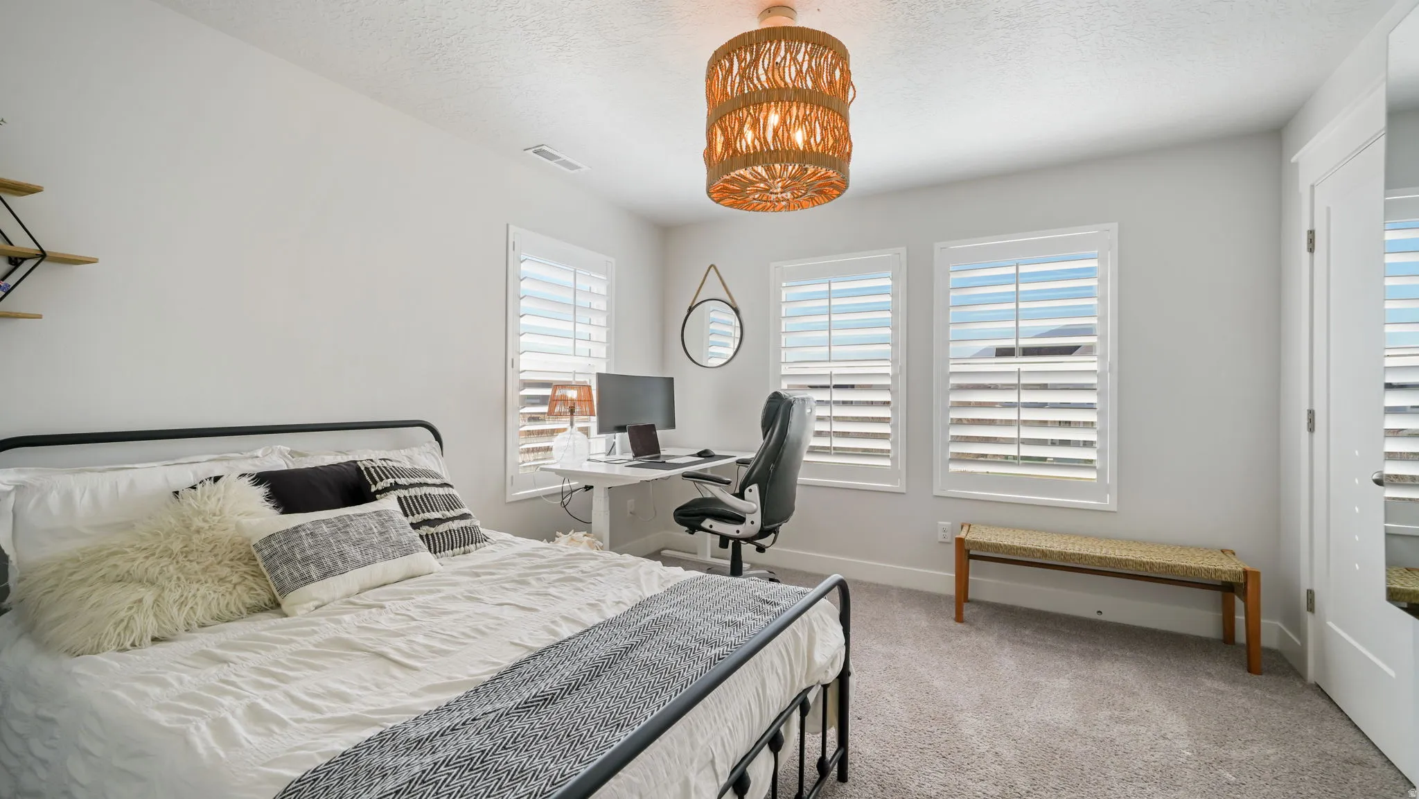 Bedroom with light colored carpet, a chandelier, an office area, and a textured ceiling
