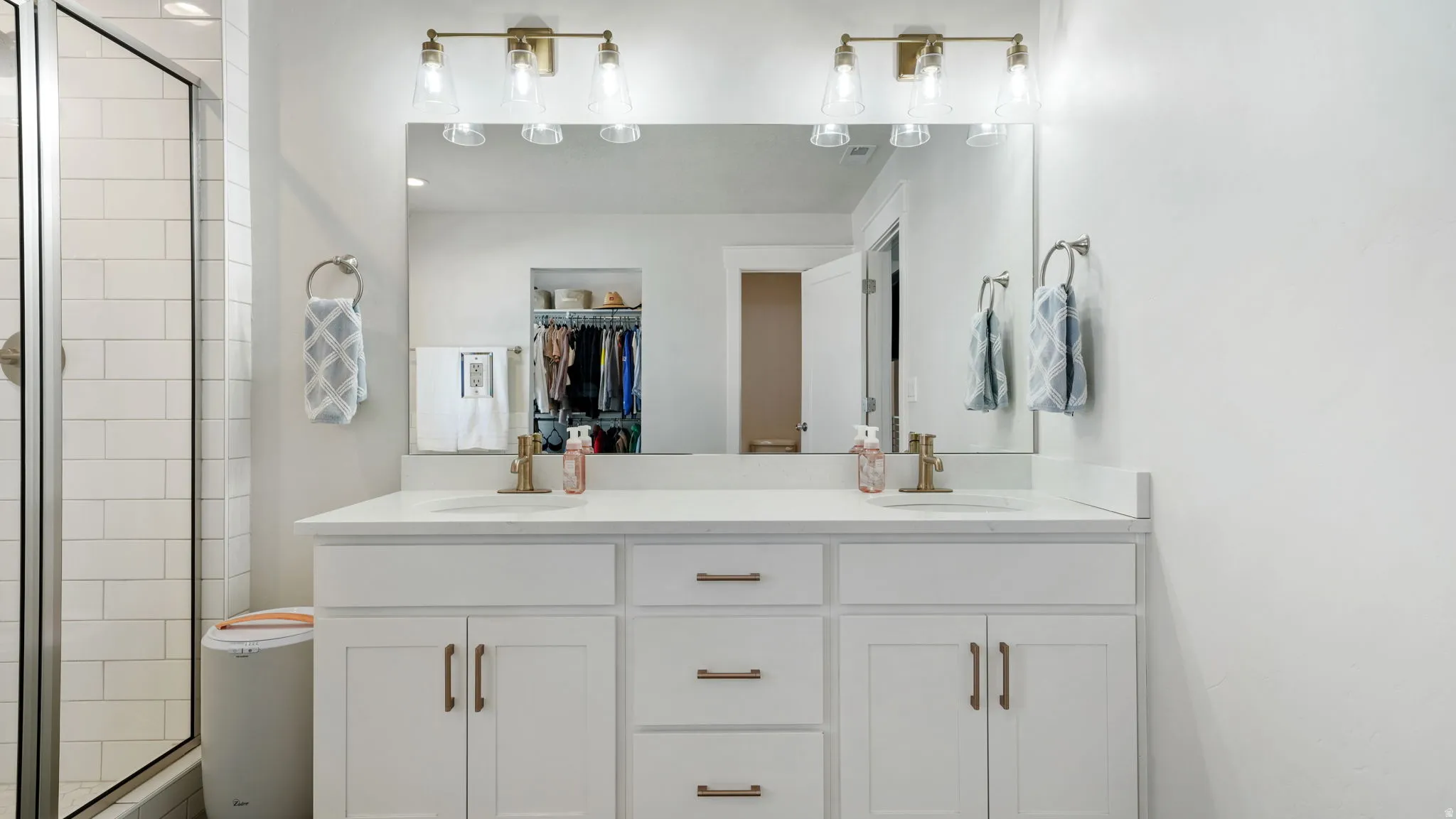 Full bath featuring double vanity, a shower stall, and a walk in closet