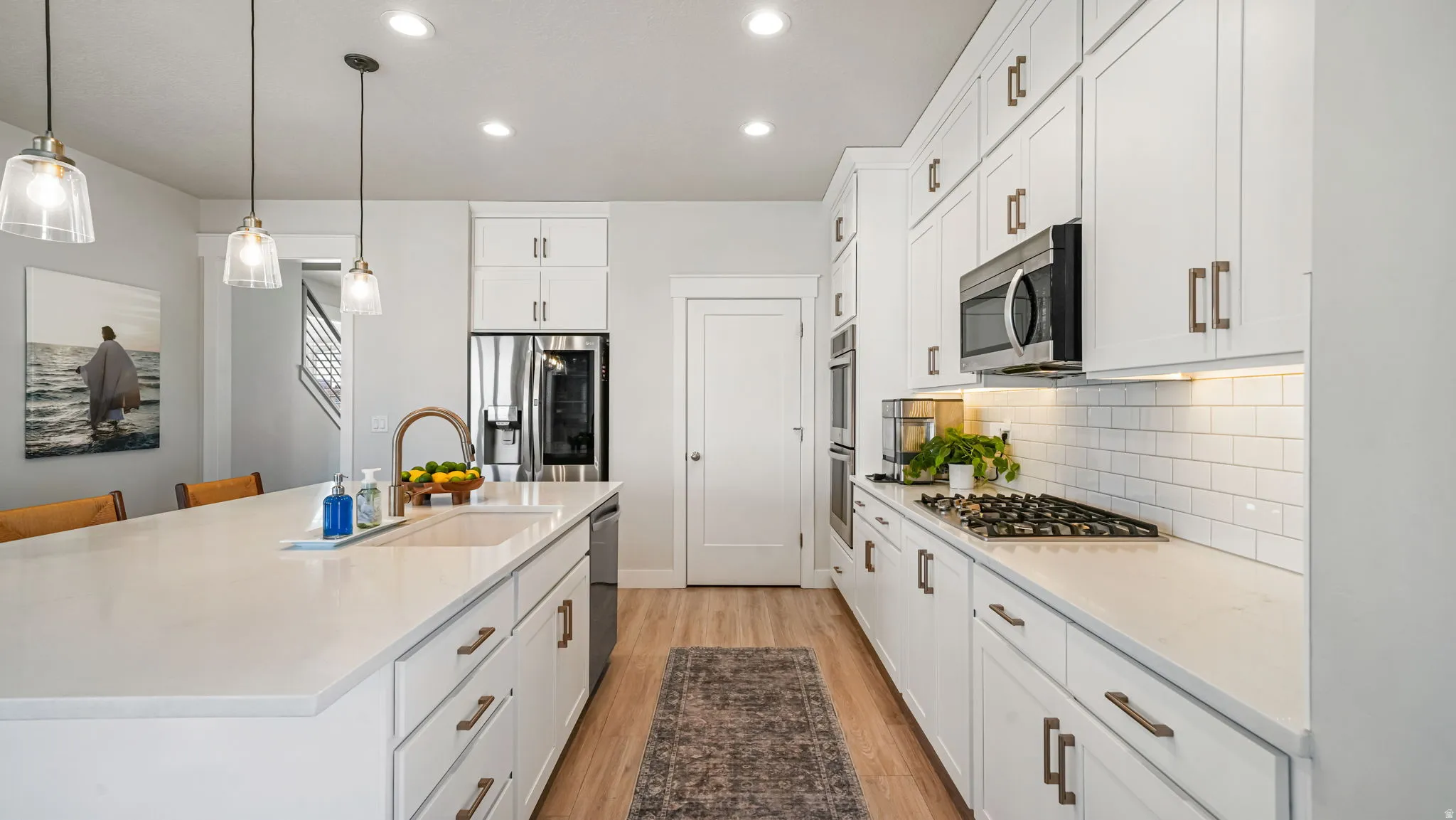 Kitchen with white cabinets, an island with sink, and light stone countertops