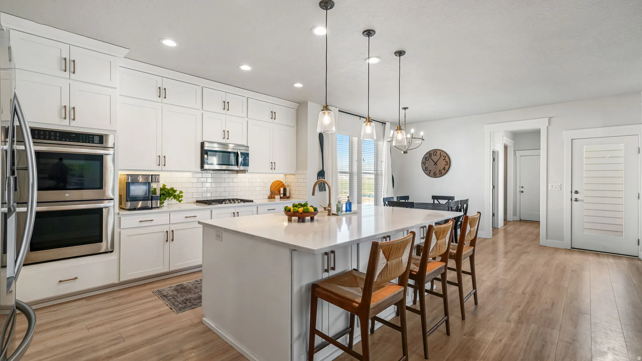 Kitchen featuring a breakfast bar, stainless steel appliances, decorative backsplash, and white cabinetry