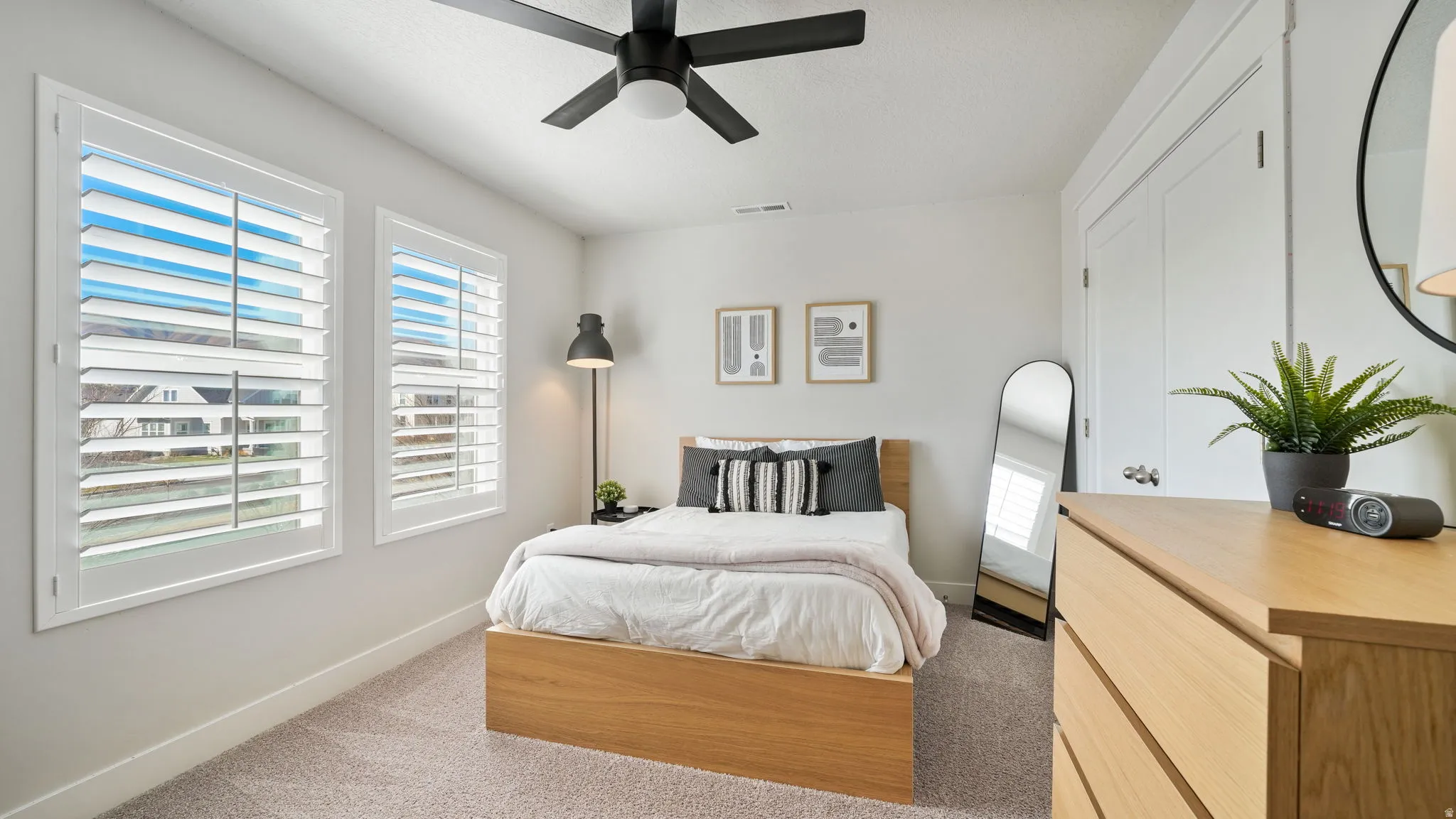 Bedroom featuring multiple windows, light colored carpet, and ceiling fan