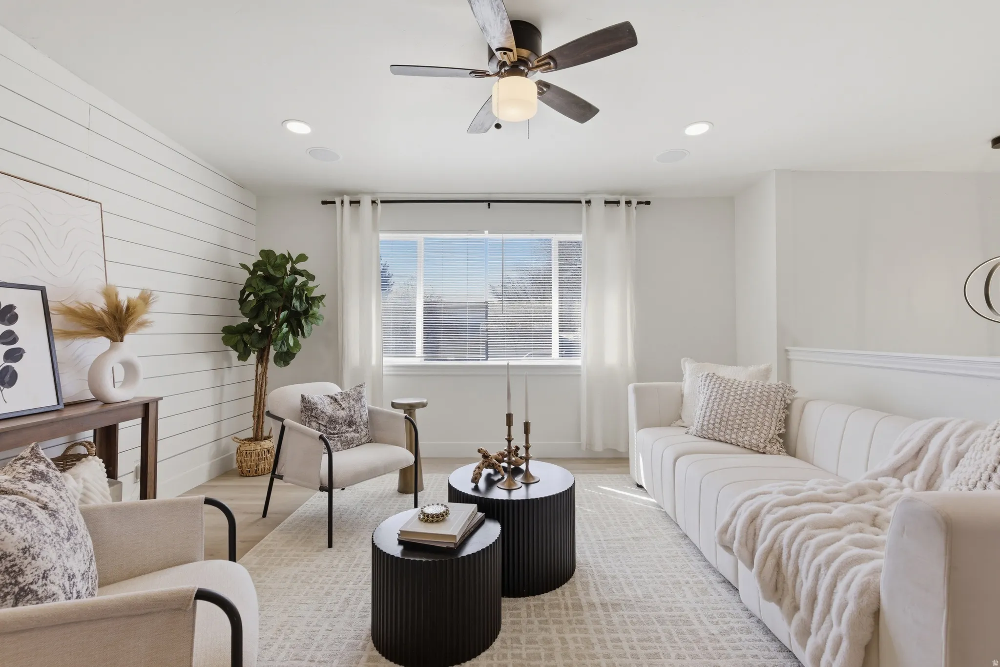 Living room featuring a ceiling fan, light wood-type flooring, wood walls, and recessed lighting