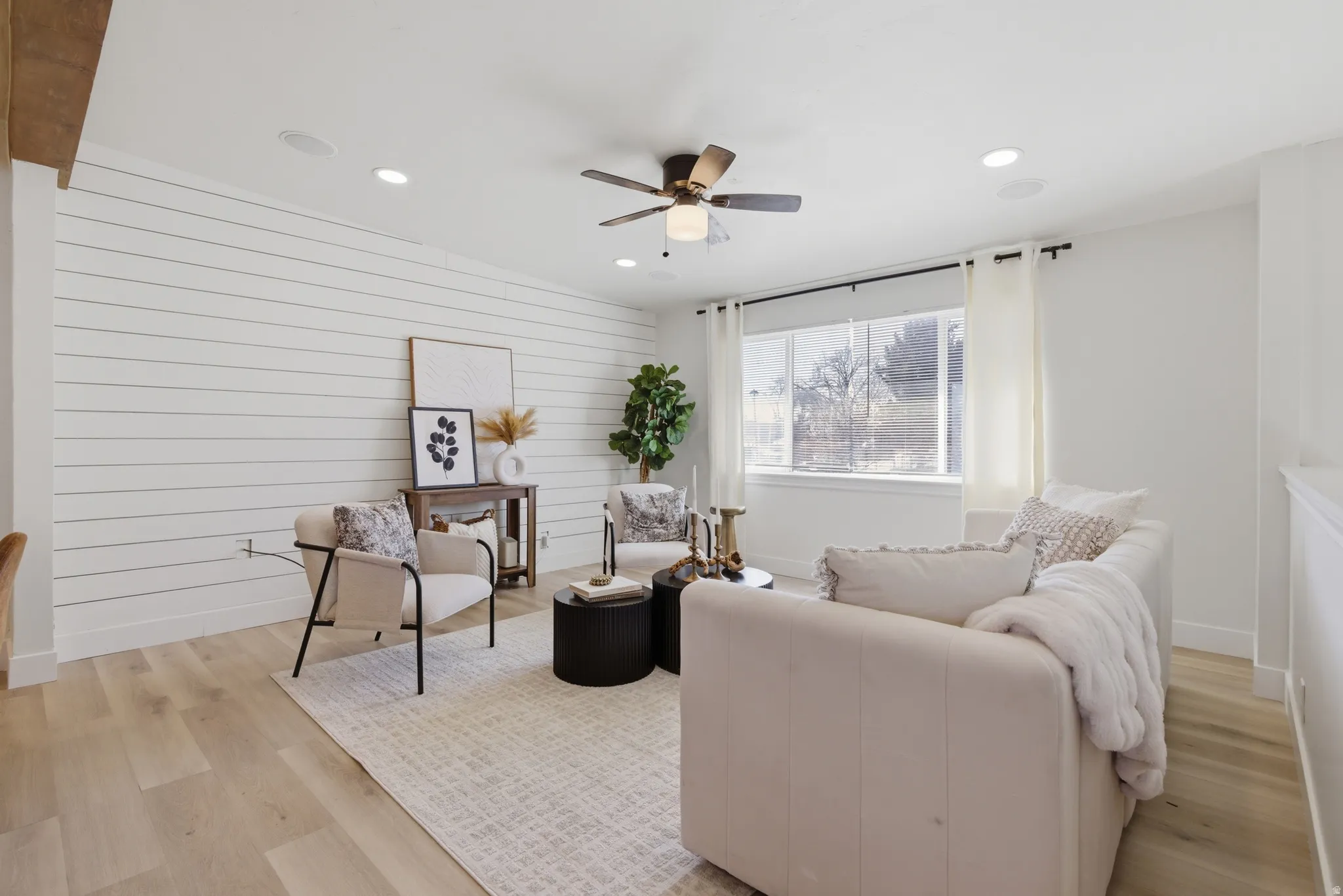 Living room featuring recessed lighting, light wood-style flooring, ceiling fan, and wood walls