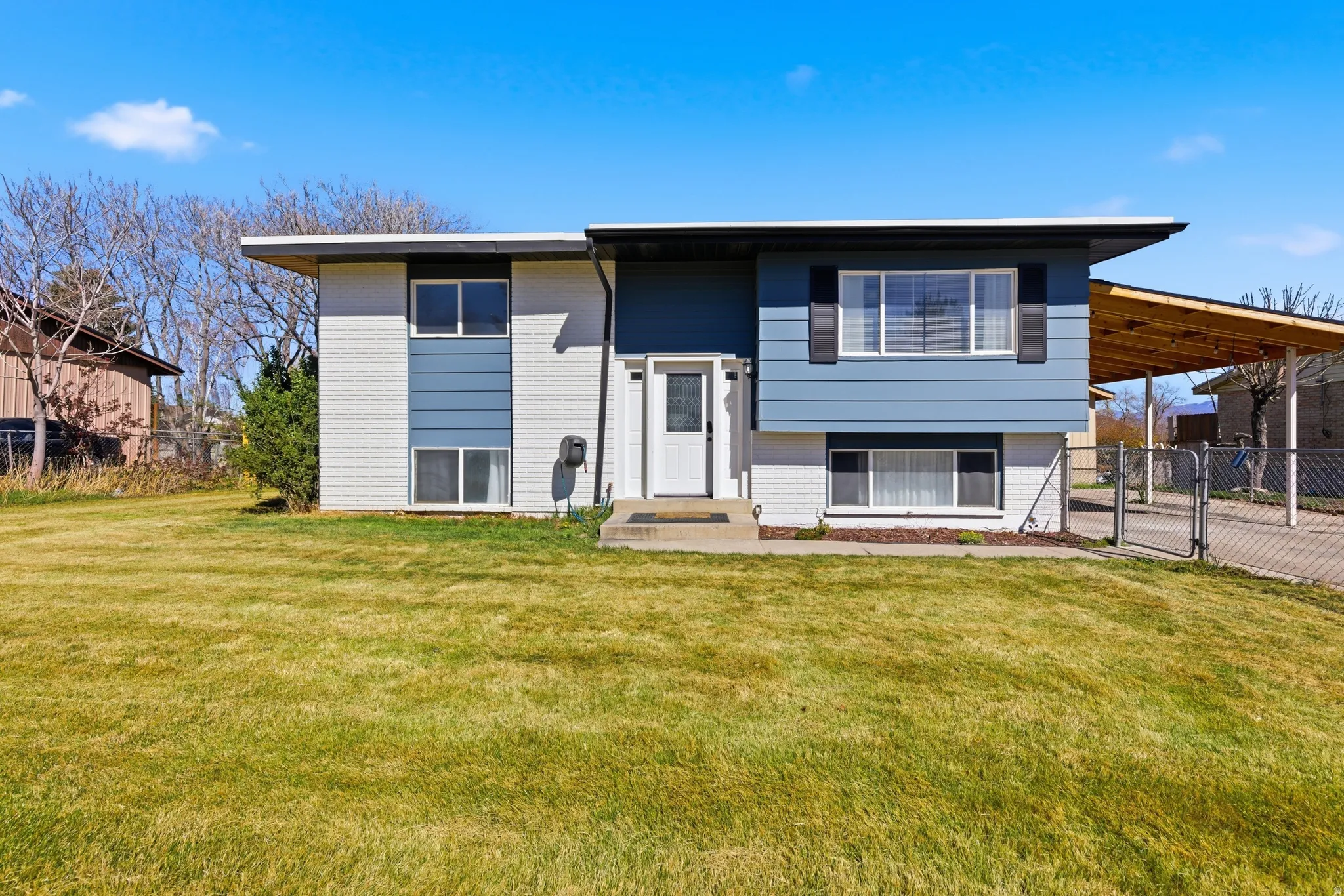 Raised ranch featuring brick siding, a gate, and an attached carport