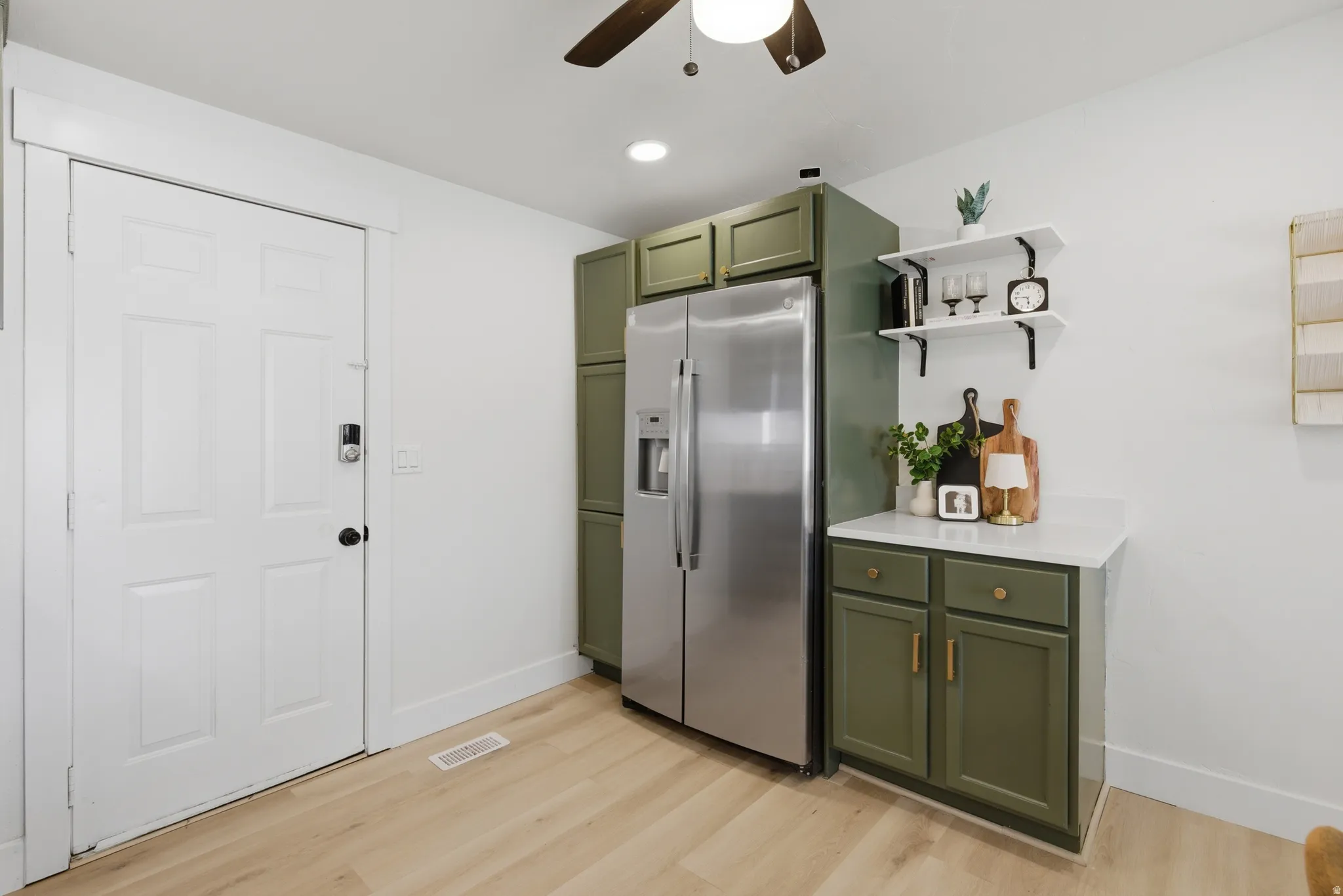 Kitchen featuring green cabinetry, stainless steel fridge, ceiling fan, light wood-style floors, and open shelves