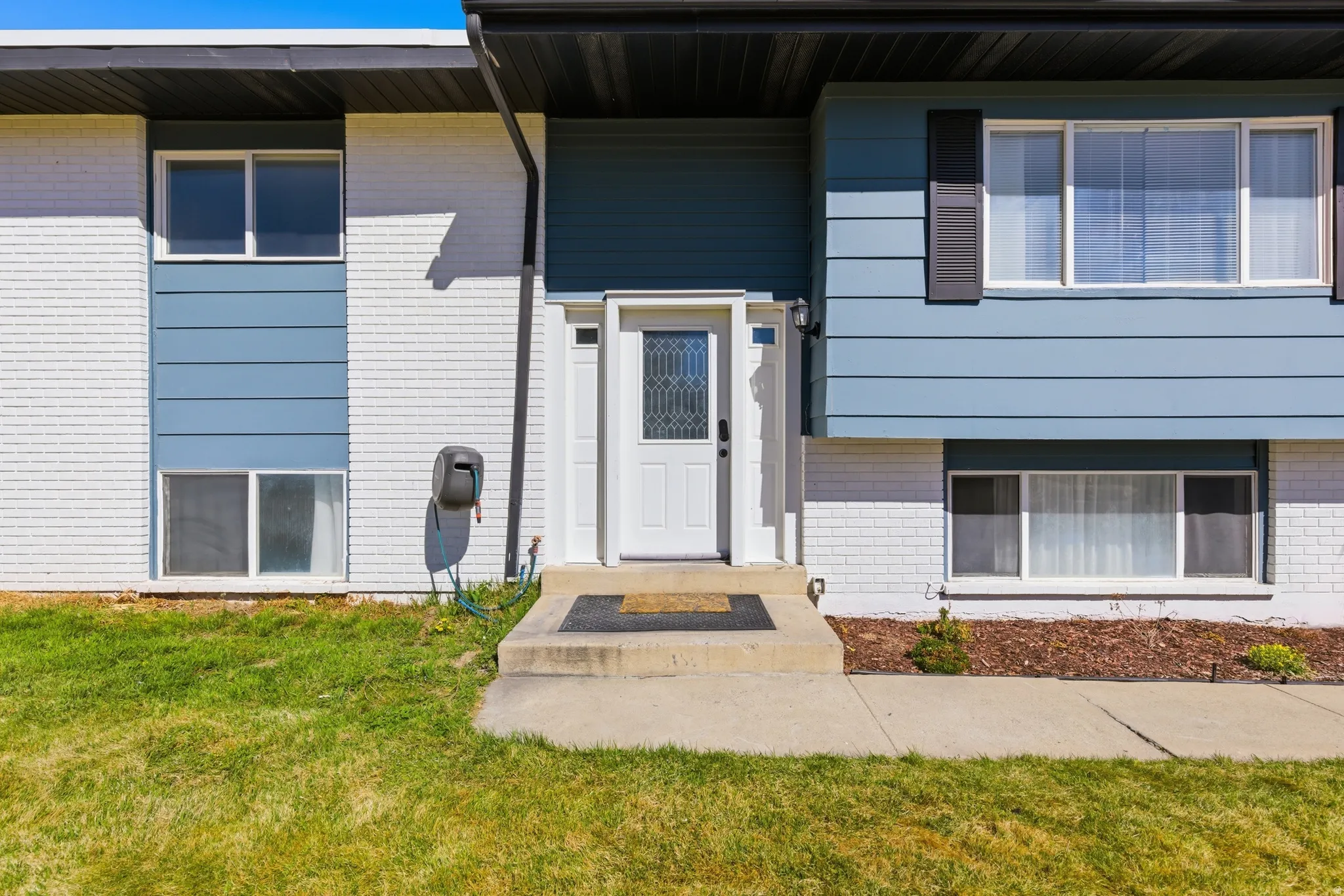 Entrance to property featuring brick siding and a lawn