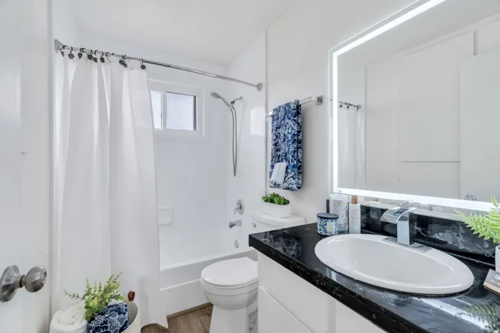 Full bath featuring vanity, shower / bath combination with curtain, and light wood-style floors