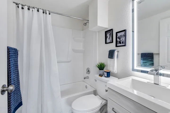 Full bath with a textured wall, vanity, and shower / tub combo with curtain