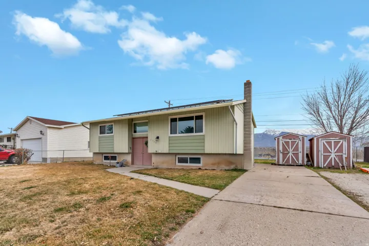 Split foyer home with a storage unit, a chimney, and a front yard