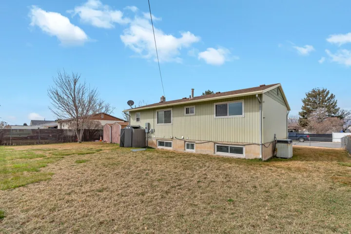 Rear view of house featuring a fenced backyard and a storage shed
