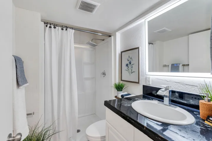 Full bathroom with a shower stall, vanity, and a textured wall