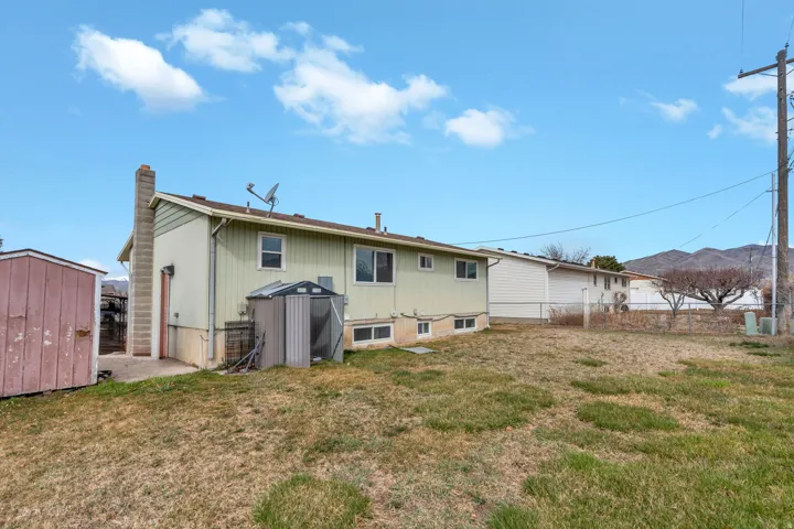 Rear view of house featuring a storage shed and a chimney