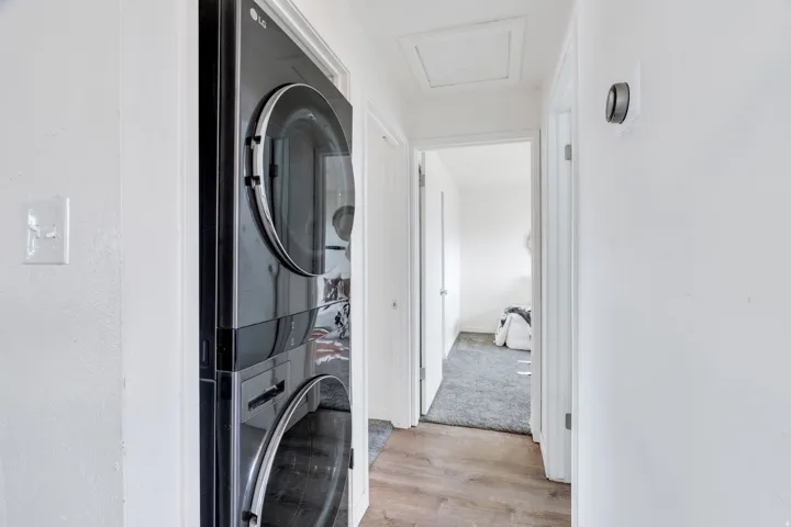 Laundry area with light wood finished floors and stacked washer and dryer