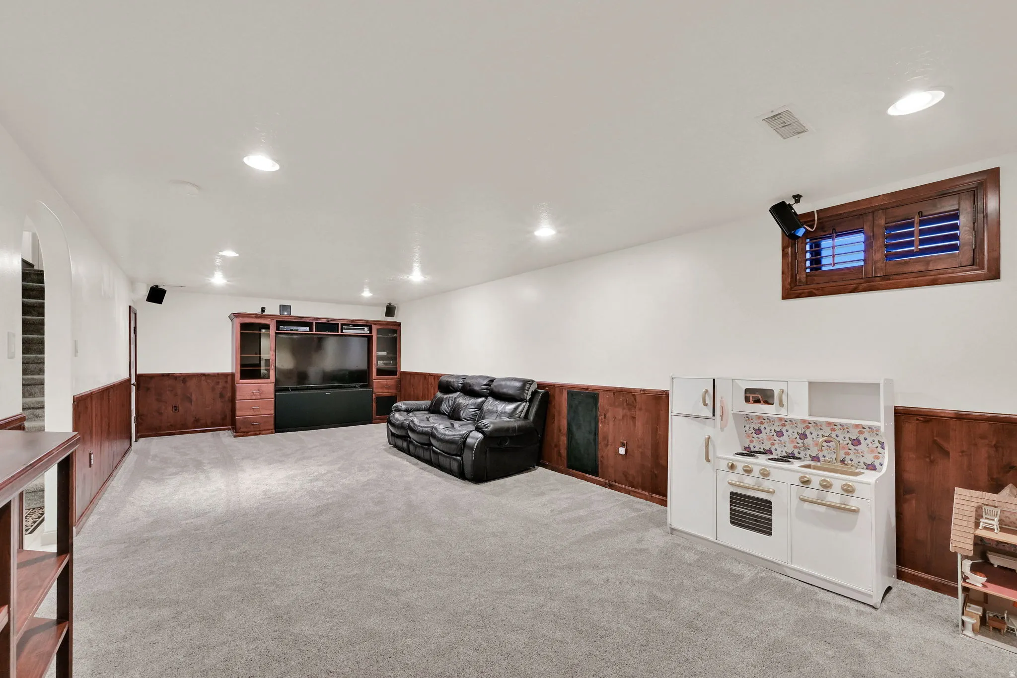 Living room with wainscoted walls, light carpet, built ins, and recessed lighting